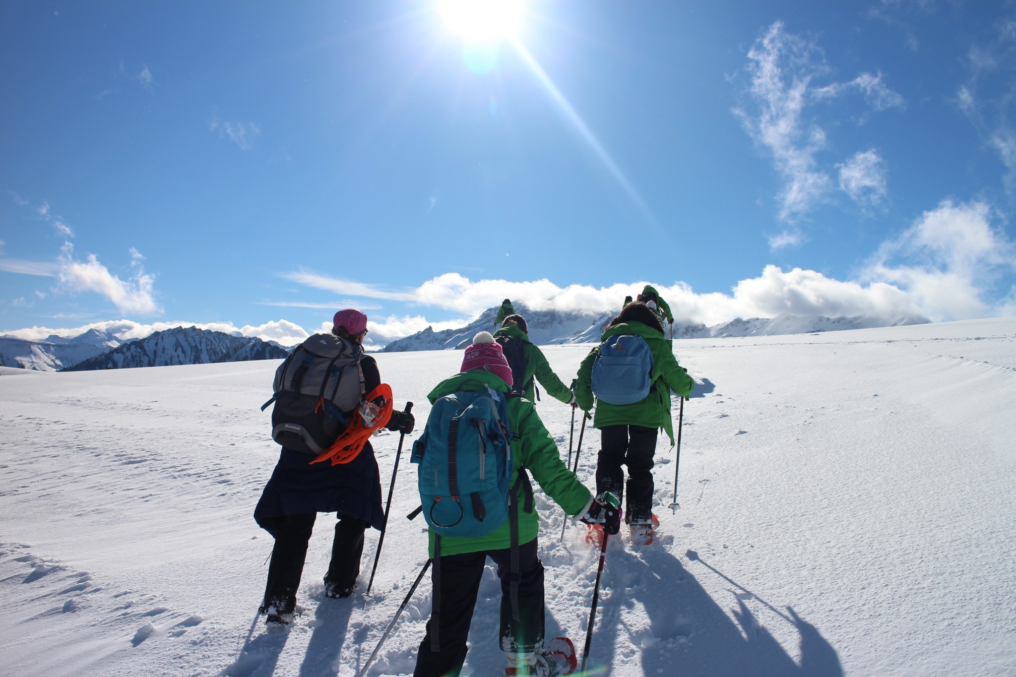 Skiers crossing a snow plateau under a clear alpine sky