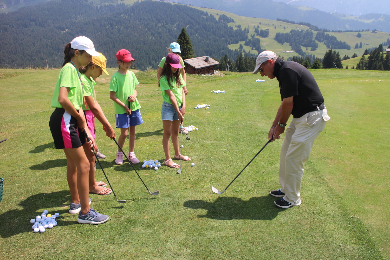Campers taking a golf lesson with a coach on a mountain course