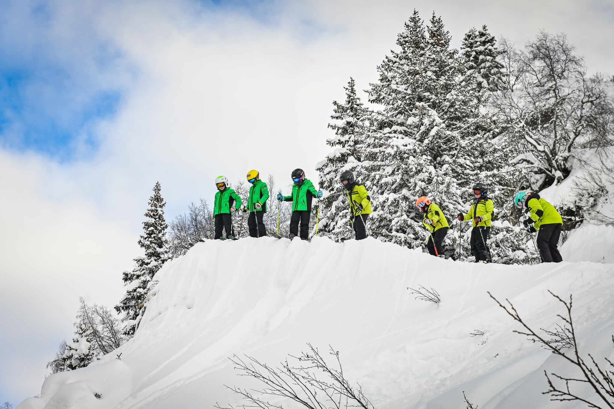 Camp group gathered on a snow-covered ridge among the pines